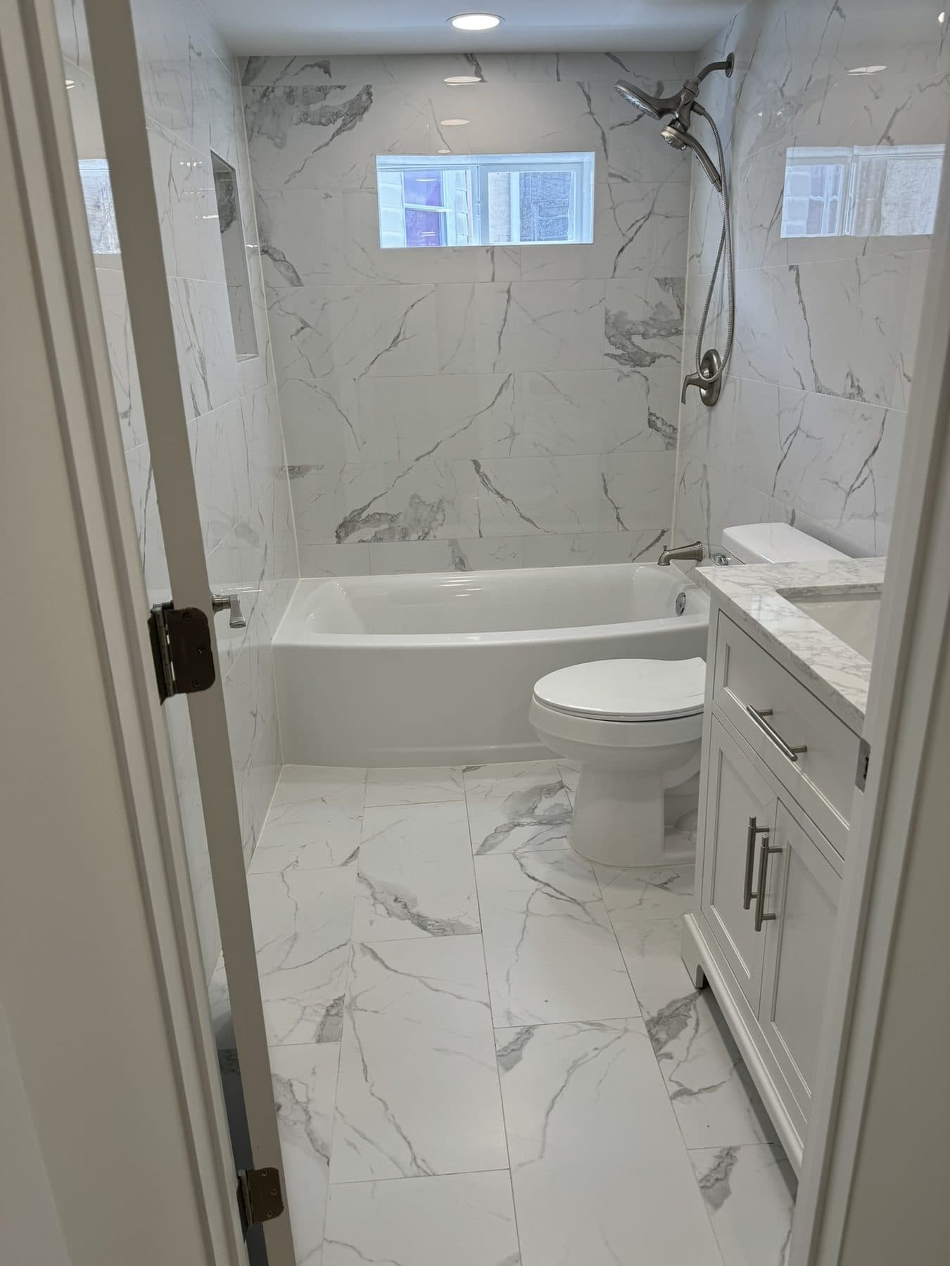 Full bathroom with marble-look tile, tub and LED mirror in a South Philadelphia rowhome