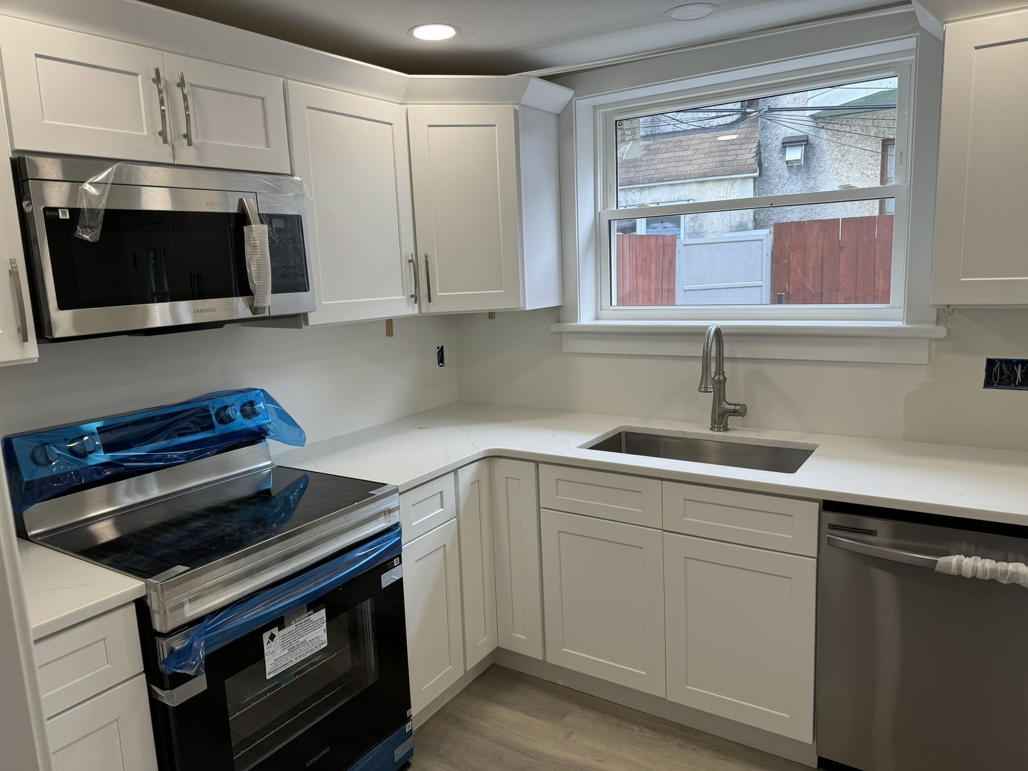 Freshly installed white shaker kitchen with quartz counters and stainless appliances during an Amazing Builders remodel near York, PA